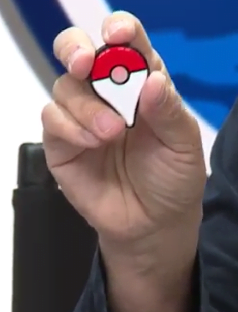 Miyamoto holding the Pokémon GO Plus. That light changes colour depending on what is happening, and it vibrates as well.